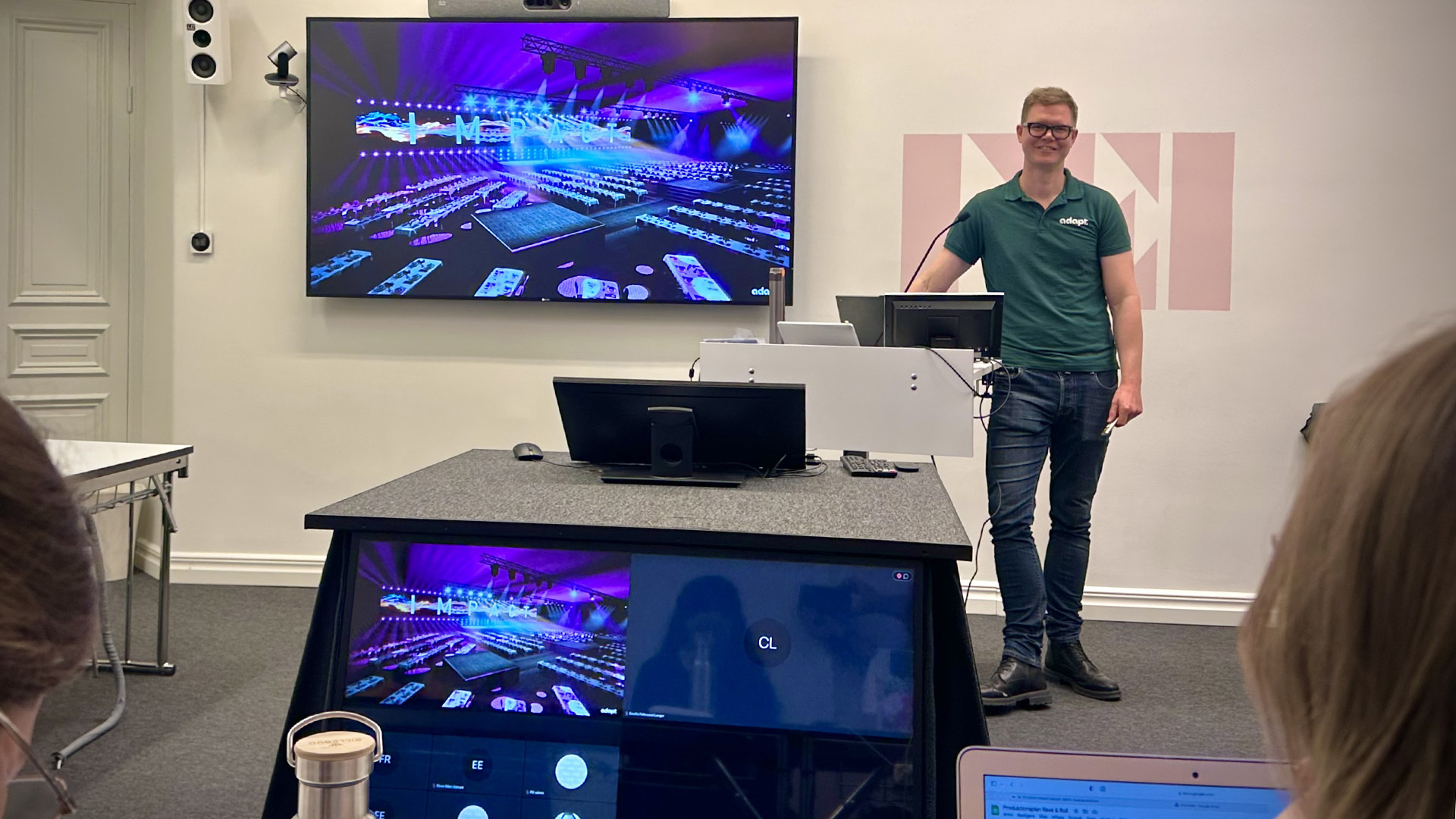 “Föreläsare från Adapt som presenterar eventdesign med en projektion på skärmen i bakgrunden.”