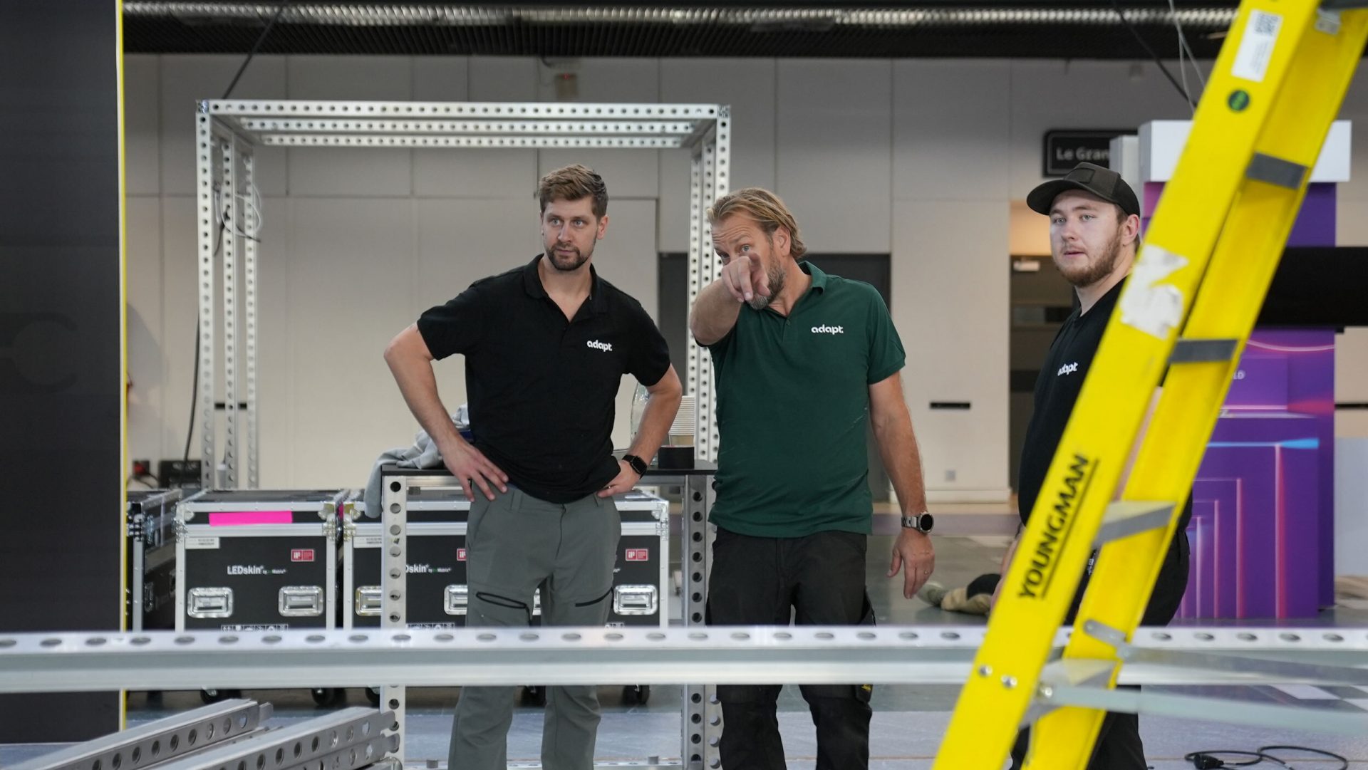 Tre tekniker från Adapt diskuterar monteringen av beMatrix-ramar på en mässa.