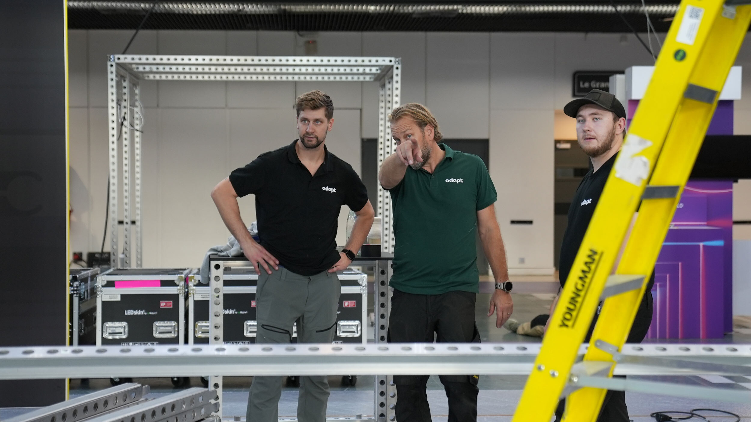 Tre tekniker från Adapt diskuterar monteringen av beMatrix-ramar på en mässa.