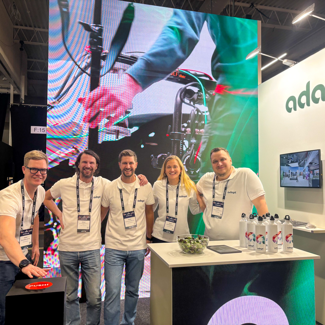 Gruppbild på Adapt-teamet i deras monter på Möten & Event 2025, framför en stor LED-skärm som visar en teknisk installation.