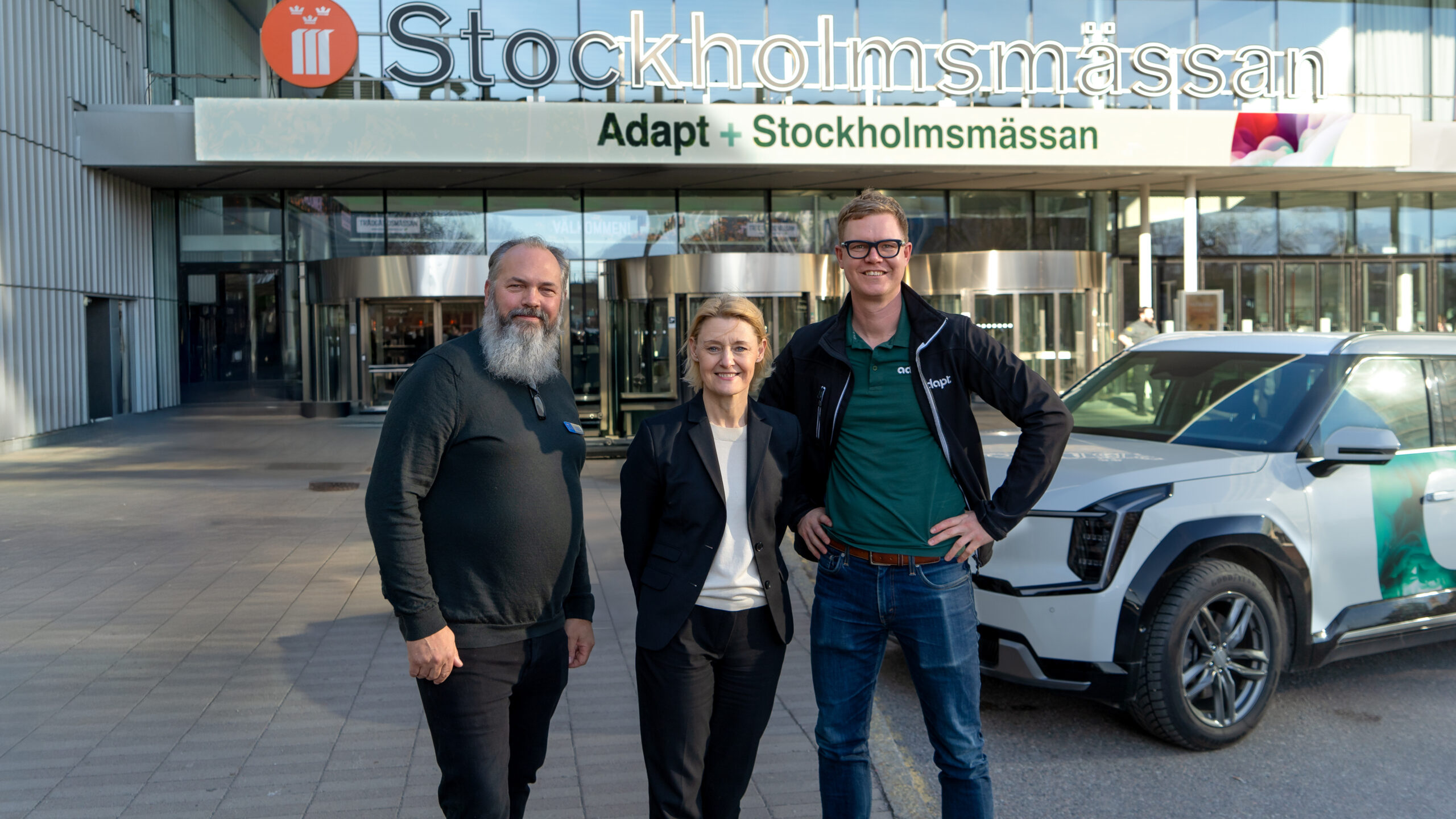 företrädare för Stockholmsmässan och Adapt framför entren till mässahallen i Älvsjö utanför Stockholm.