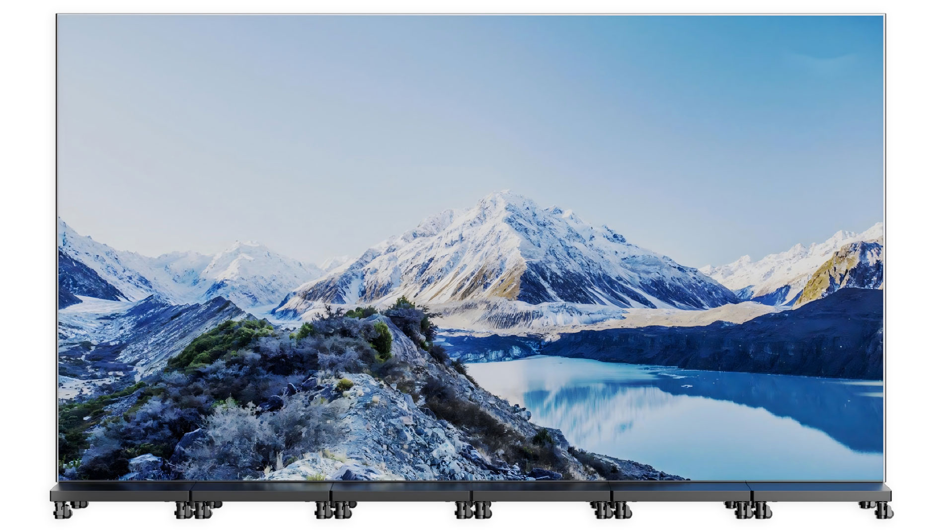A large, high-definition screen displays a scenic view of snow-capped mountains reflected in a calm blue lake under a clear sky, with rocky hills and greenery in the foreground.