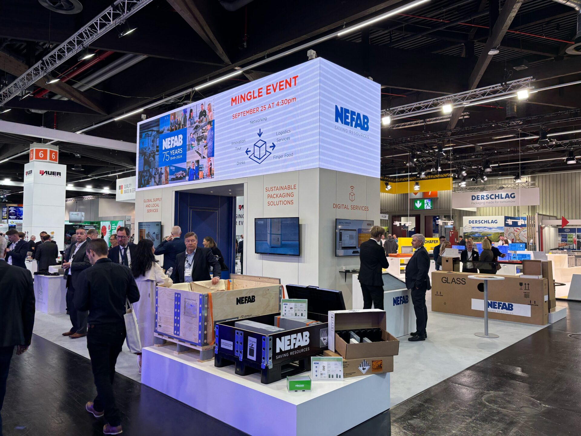 People attend a trade show with a NEFAB booth displaying sustainable packaging solutions. Various boxes and screens are showcased, with event information on a large digital sign above. Other exhibitor stands are visible in the background.