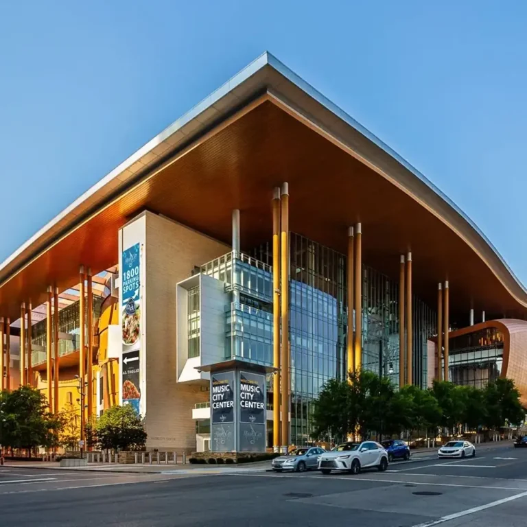 The Music City Center building in Nashville, featuring a modern glass and wood exterior with banners advertising parking and an event.