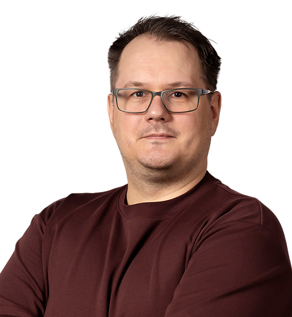 A man with short hair and glasses wearing a burgundy shirt.